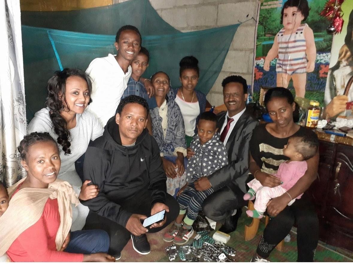 A group of adults and children gathered together in a home